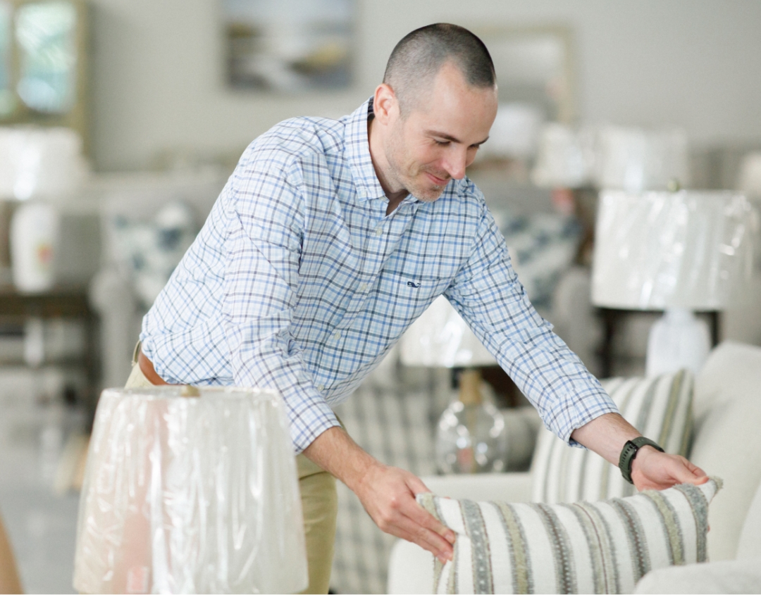 Store owner fluffing pillow in Charlotte Furniture Showroom